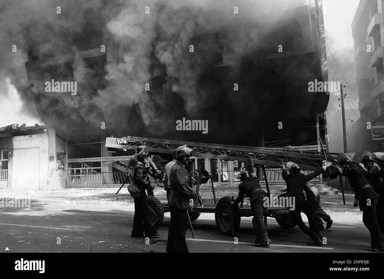 Still wearing riot helmets, Iranian police help wheel a piece of fire ...