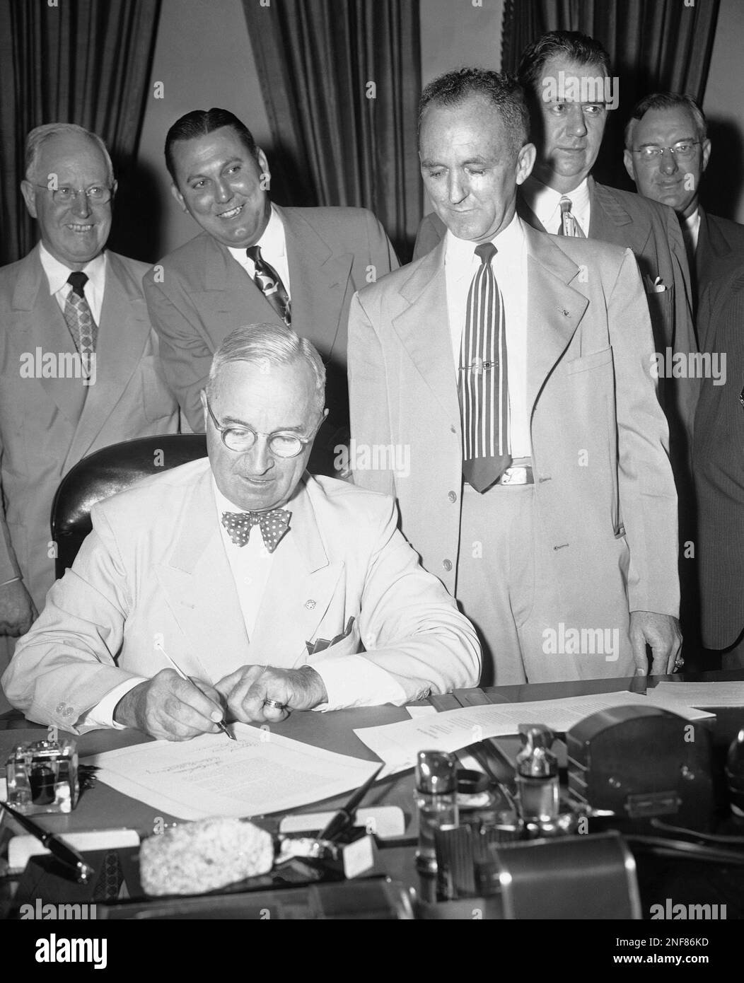 President Harry Truman, seated, signs bill which brings employees of ...
