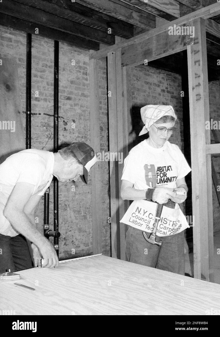 Former President Jimmy Carter measures plywood while Rosalynn looks on, during a work session in