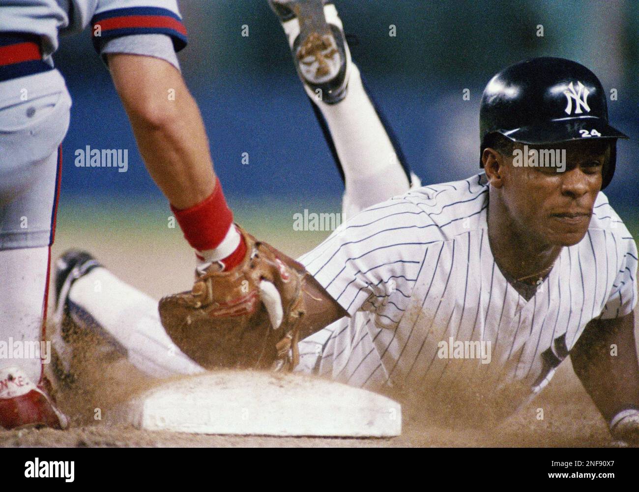 Rickey Henderson of the New York Yankees gets back to the bag avoiding the  glove of California Angels first baseman Wally Joyner in the first inning  at Yankee Stadium, Aug. 17, 1988.