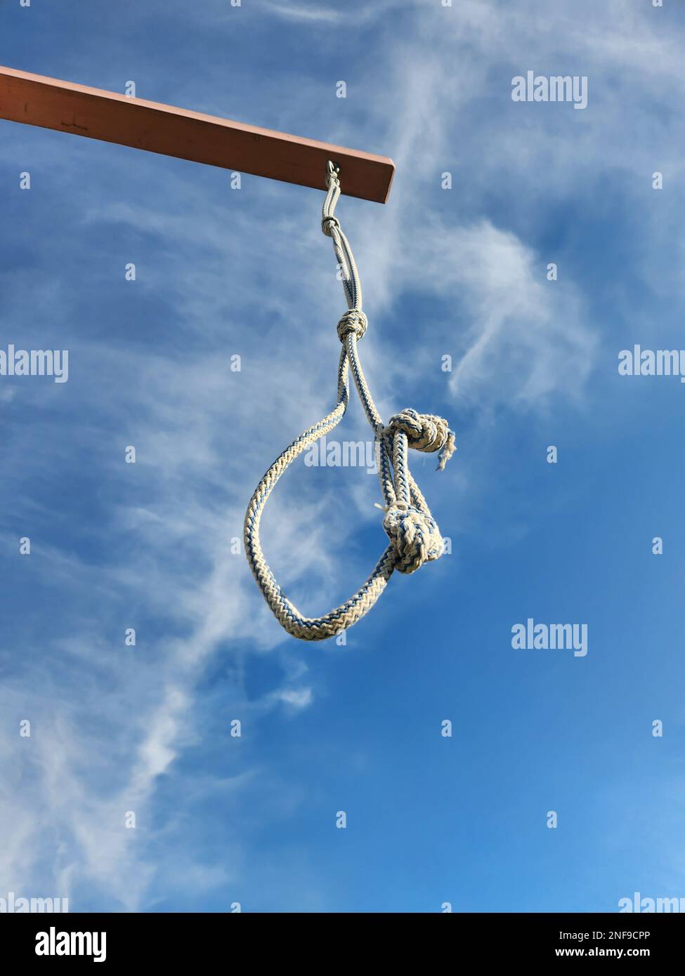 Noose from rope is suspended on gallows against blue sky with clouds. High quality photo Stock Photo