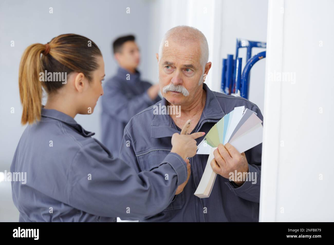 senior holding a color swatch next to female painter Stock Photo