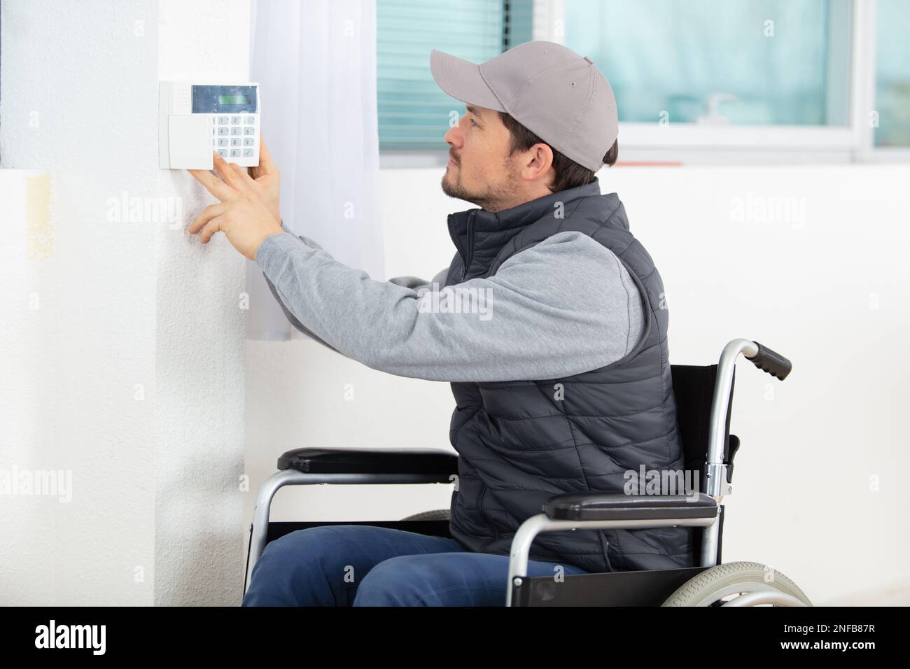 male electrician installing security system door sensor on wall Stock Photo