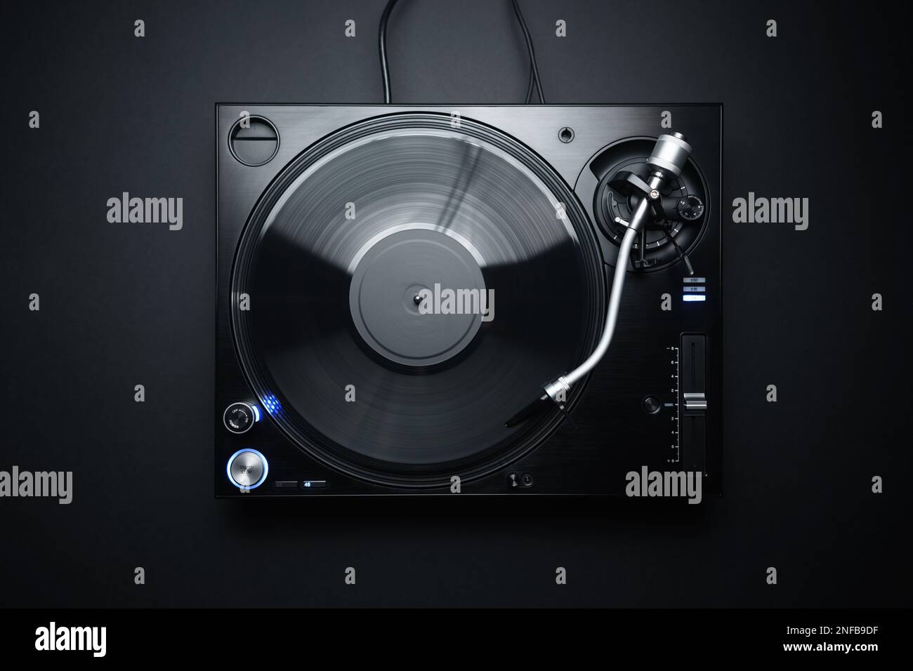 Flat lay photo of DJ turntable playing vinyl record on black background. Professional analog record player shot directly from above Stock Photo