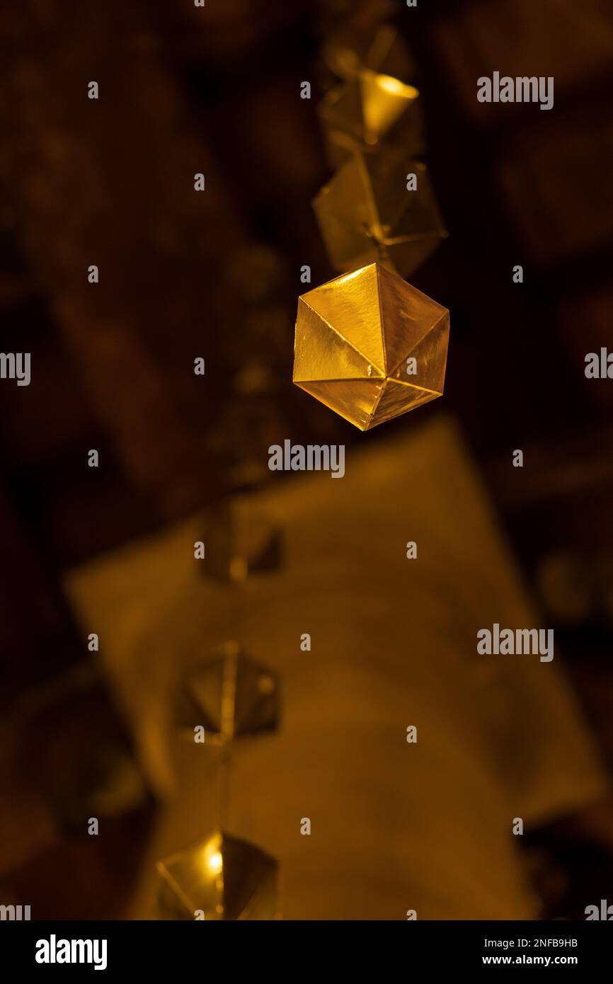 Low angle detail of a golden diamond hanging from the wooden ceiling of ...