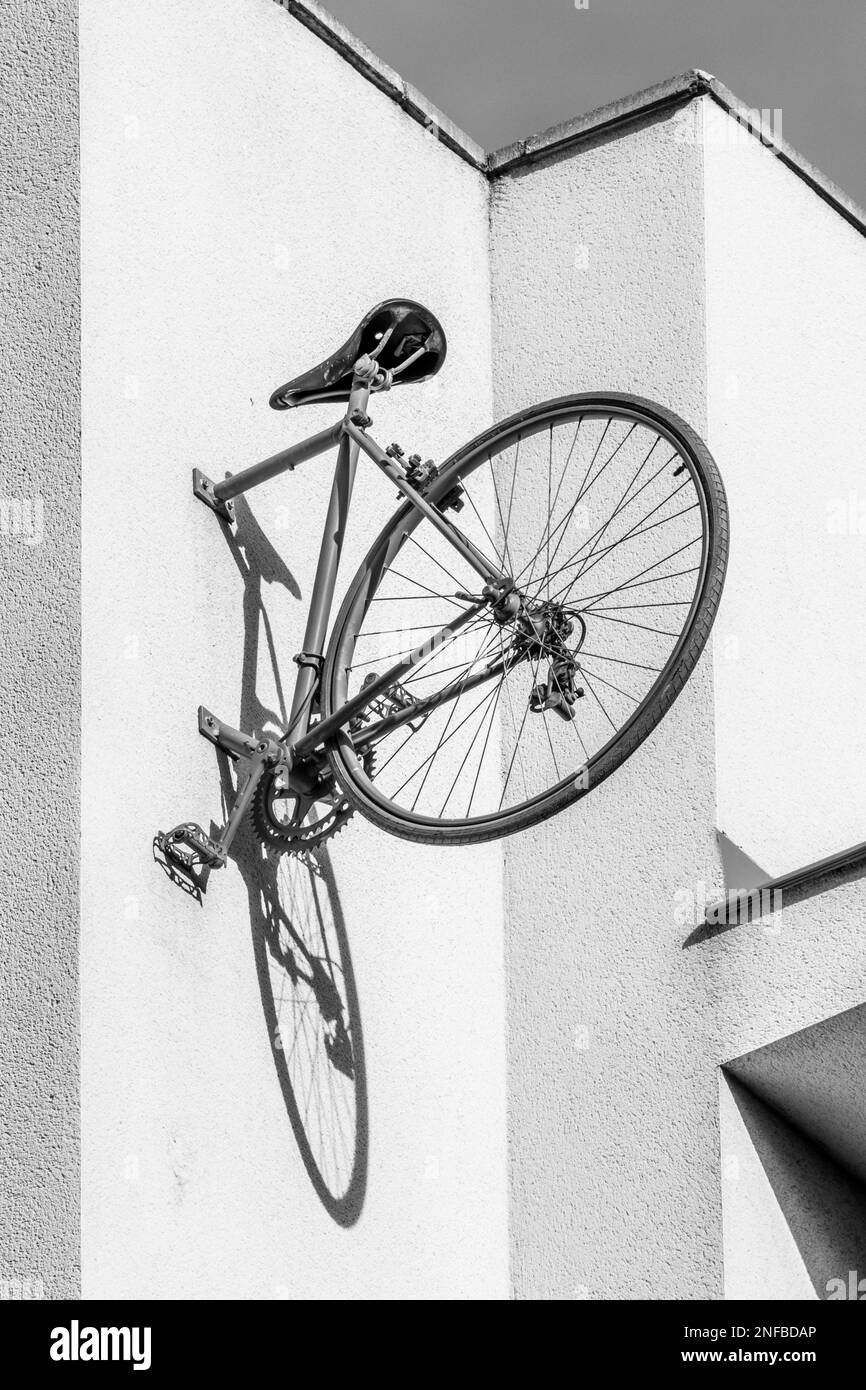 Rear half of red vintage bicycle pinned to the wall casting the shadow