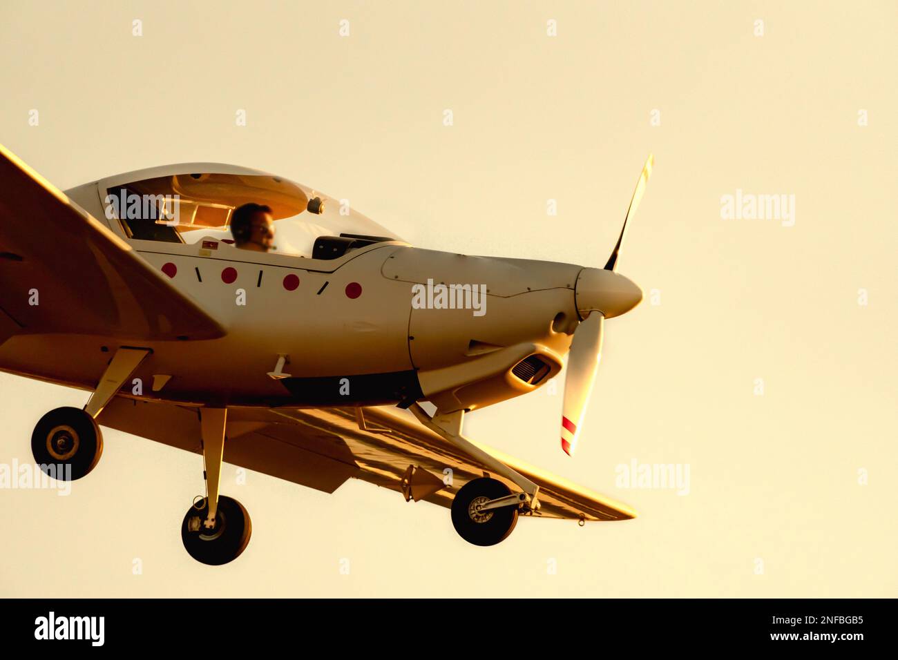 Small propeller plane landing or taking off on the runway of Sabadell airport with a totally orange blue sky in the afternoon under a twilight sun. Stock Photo