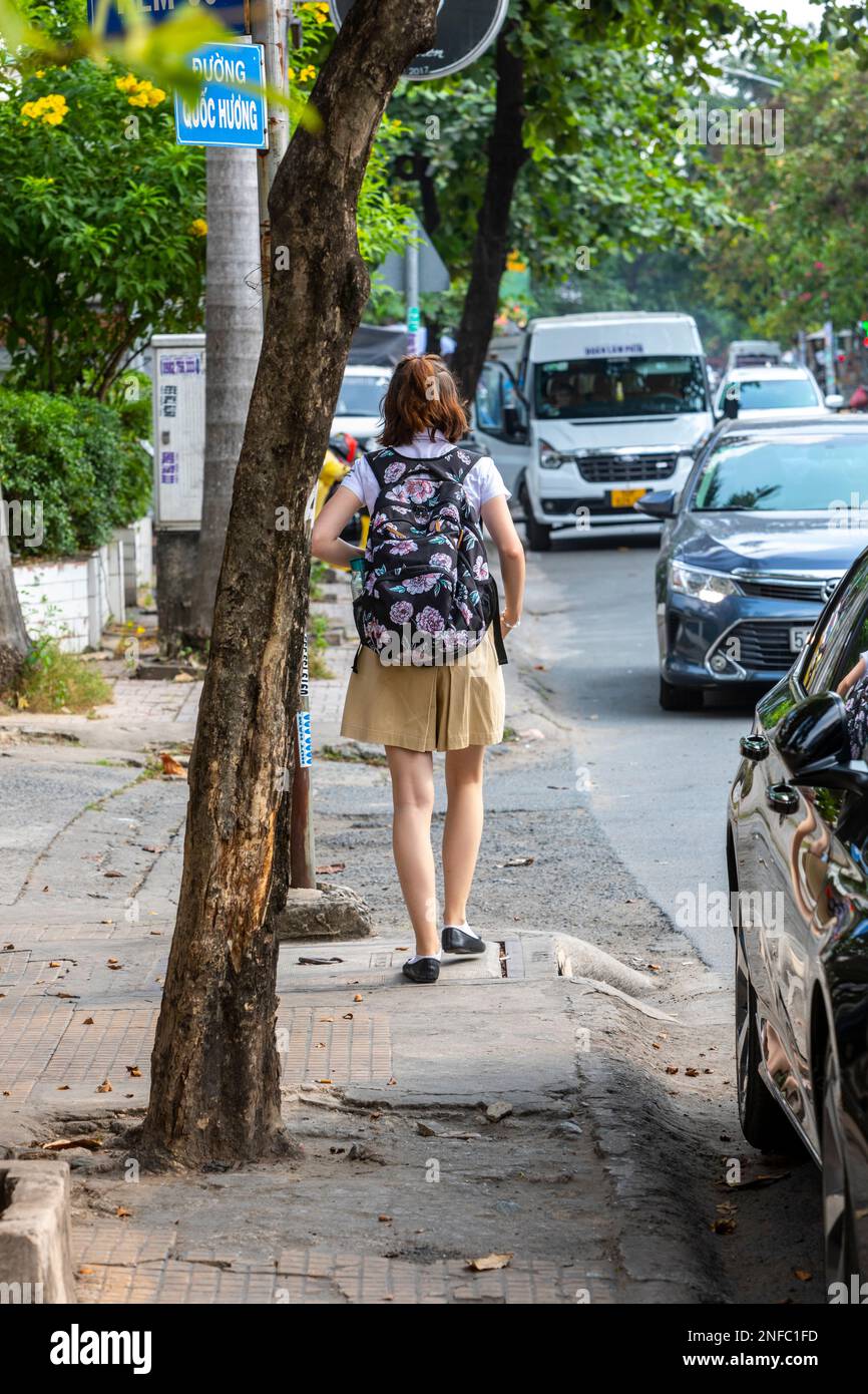 A young woman with a backpack walking in a busy street in Ho Chi Minh