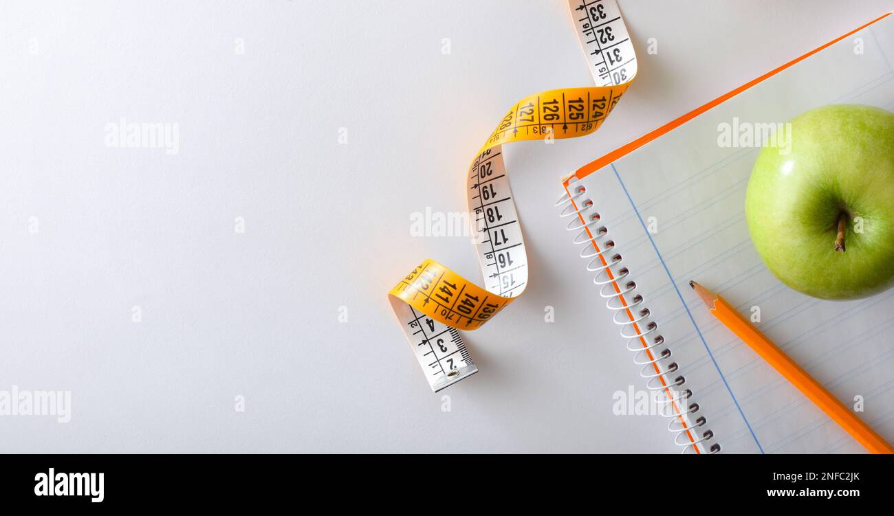 Health plan with pencil and apple on notebook on white table with tape ...