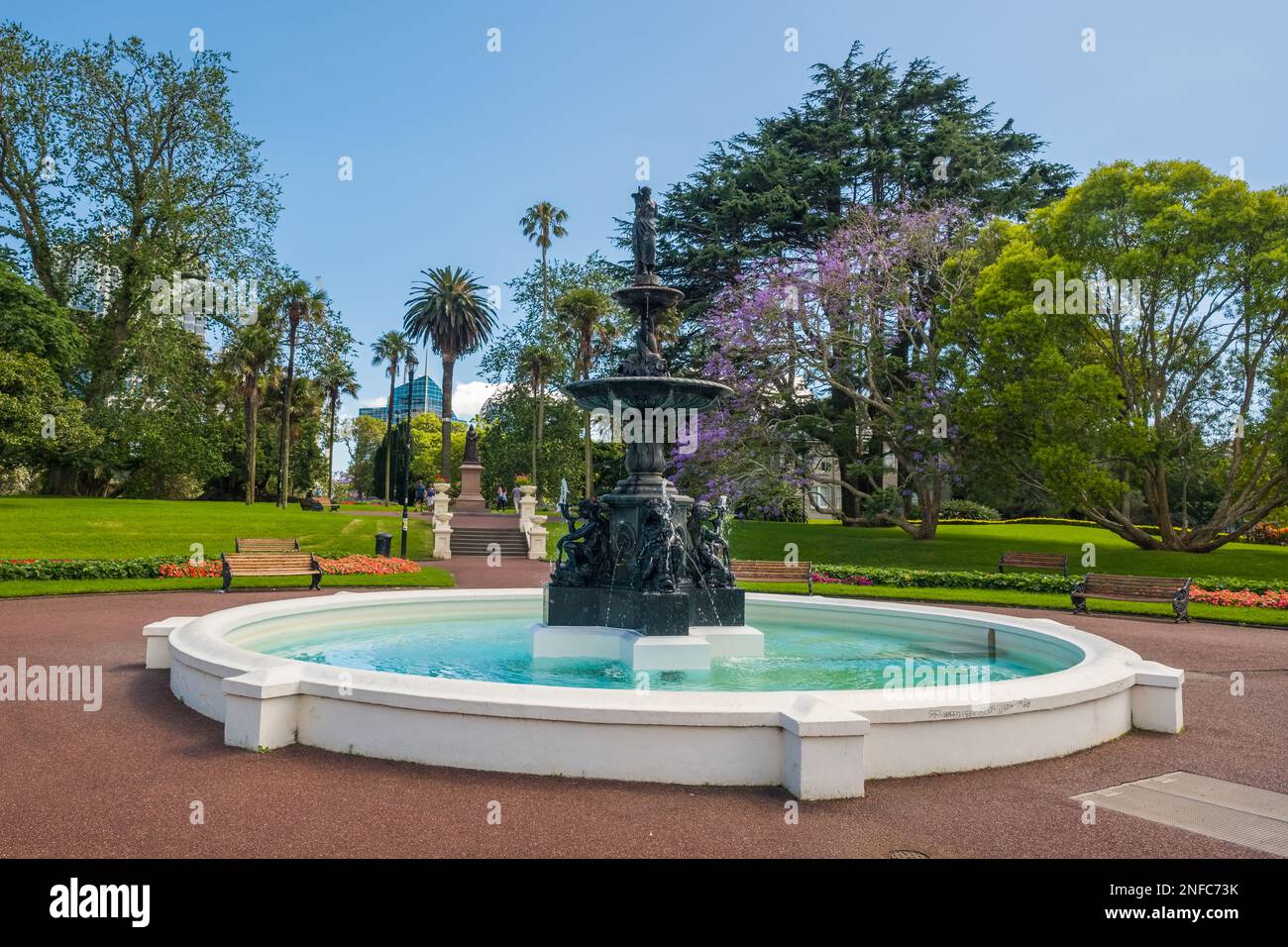 Albert Park, Auckland, New Zealand - December 28th 2022: Fountain in Albert Park in the city of Auckland, New Zealand with Jacaranda and palm trees in Stock Photo