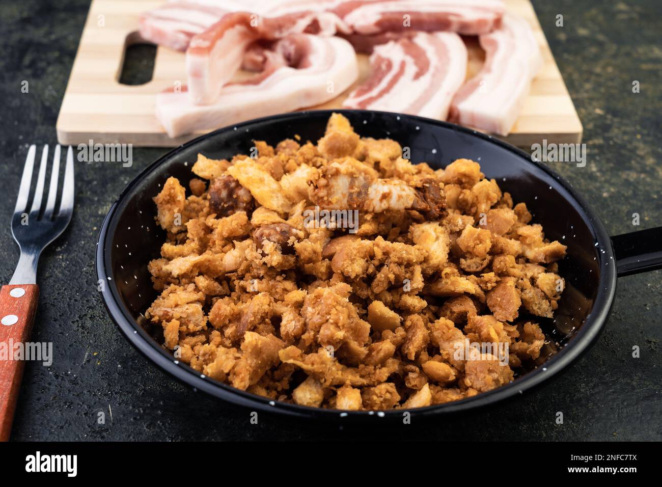 A close-up image of a kitchen counter top with cooked strips of bacon, mushrooms, and other meats, arranged on a cutting board Stock Photo