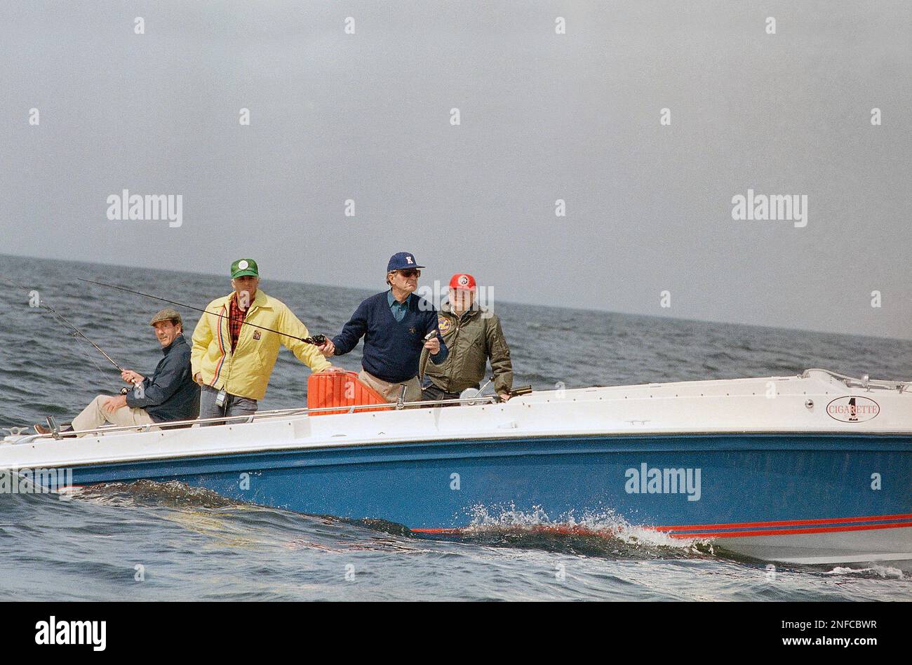 President George Bush, second from right, holds a fish in his hand as he  points in a line from his boat during a fishing excursion in the waters  near his vacation home