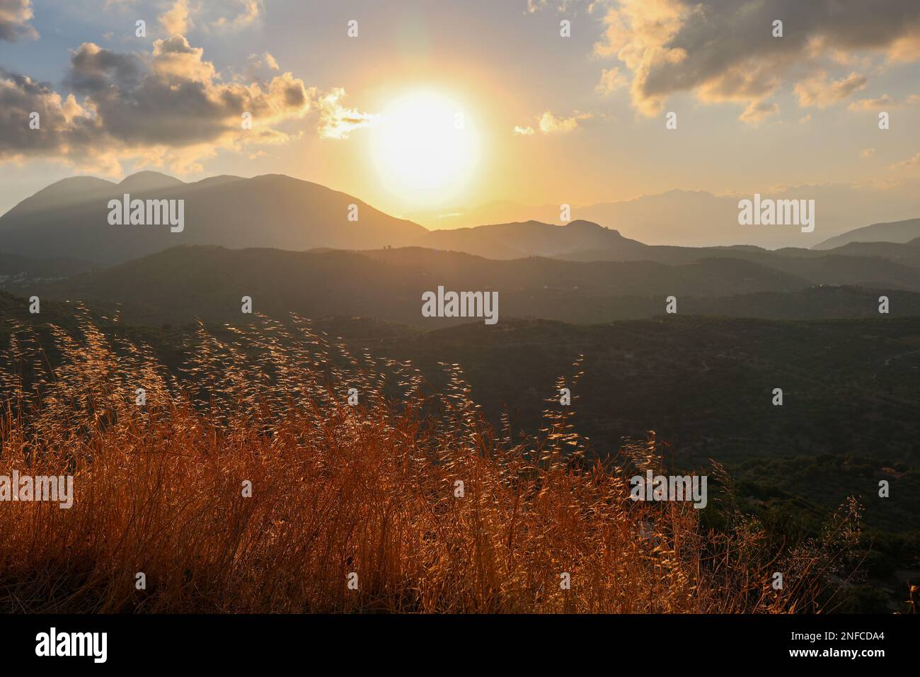Majestic mountains with the sun setting behind, casting a warm yellow ...
