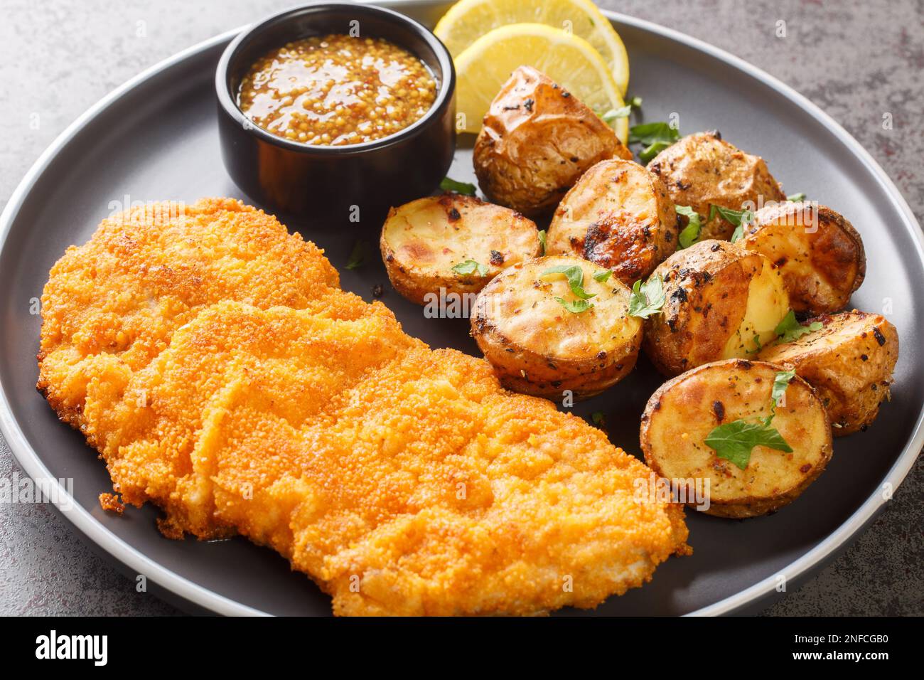 Munich schnitzel served with baked potatoes and mustard close-up in a plate on the table. horizontal Stock Photo