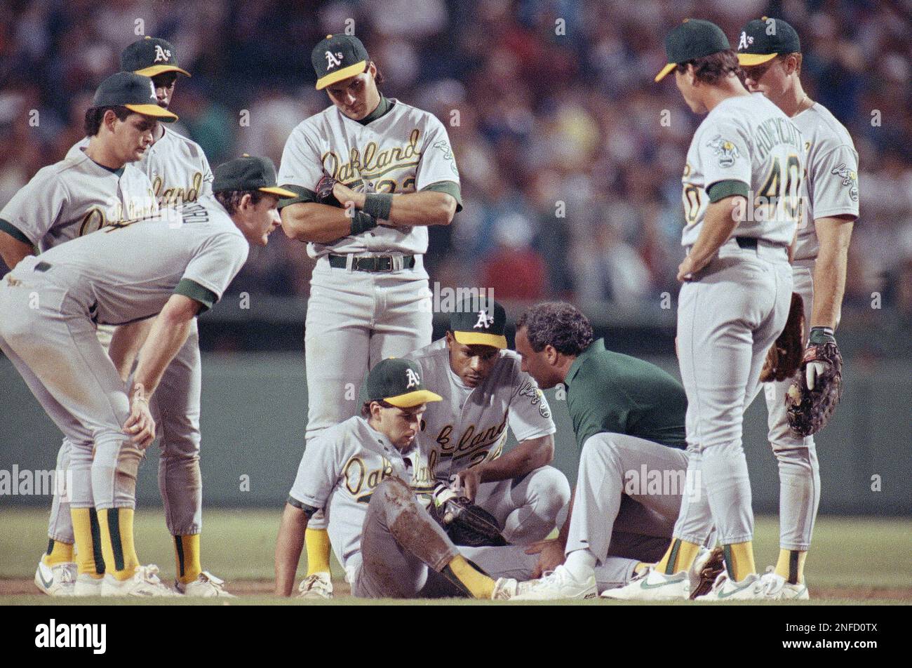 Members of the Oakland Athletics gather around shortstop Walt Weiss (7) as  a trainer attends to him in the eight inning of American League  Championship Series game against the Boston Red Sox