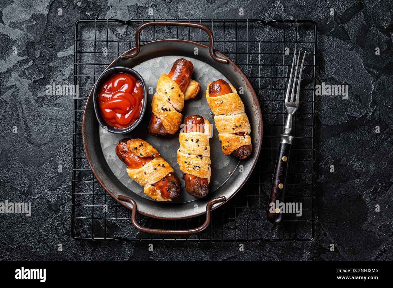 Pigs in Blanket puff pastry sausage wrap roll. Black background. Top