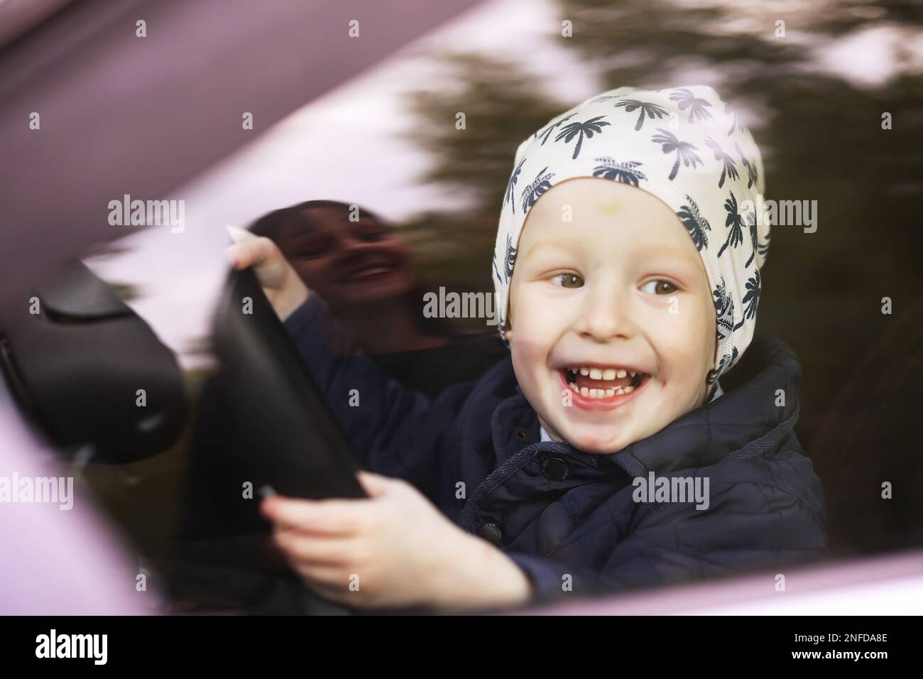 Little boy playing with a steering wheel in a car. Hands of a small