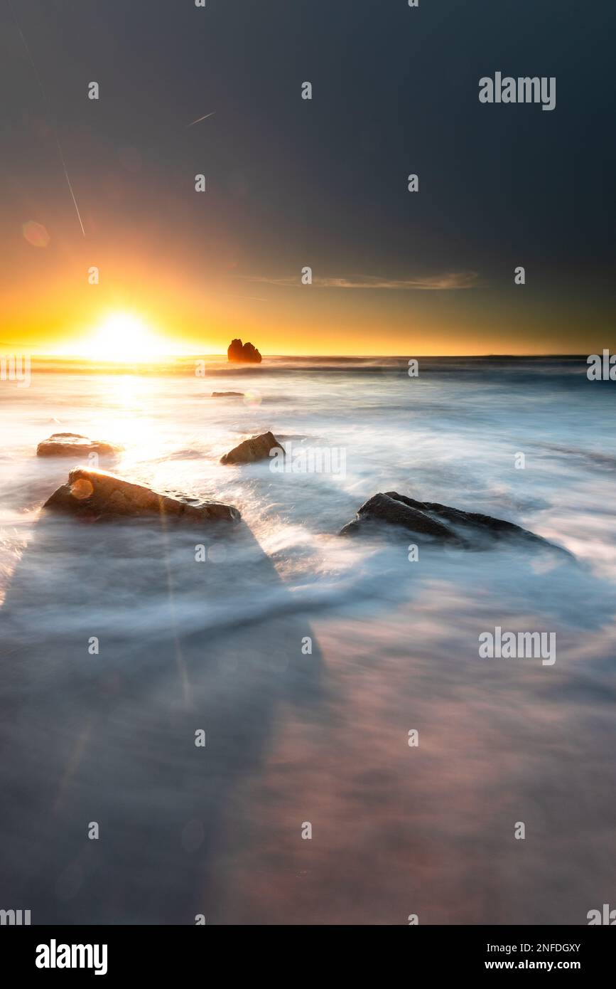 Sunset while sea waves hitting the rocks on the beach; at Ilbarritz ...