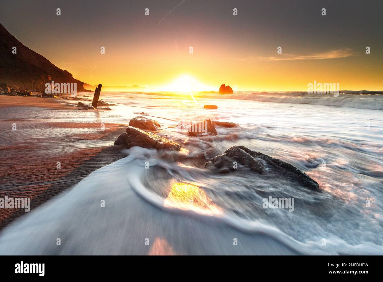Sunset while sea waves hitting the rocks on the beach; at Ilbarritz ...
