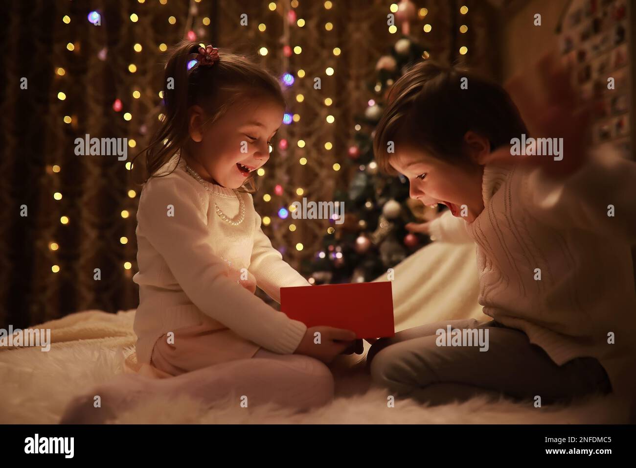 Family on Christmas eve at fireplace. Kids opening Xmas presents Christmas Eve Traditiona