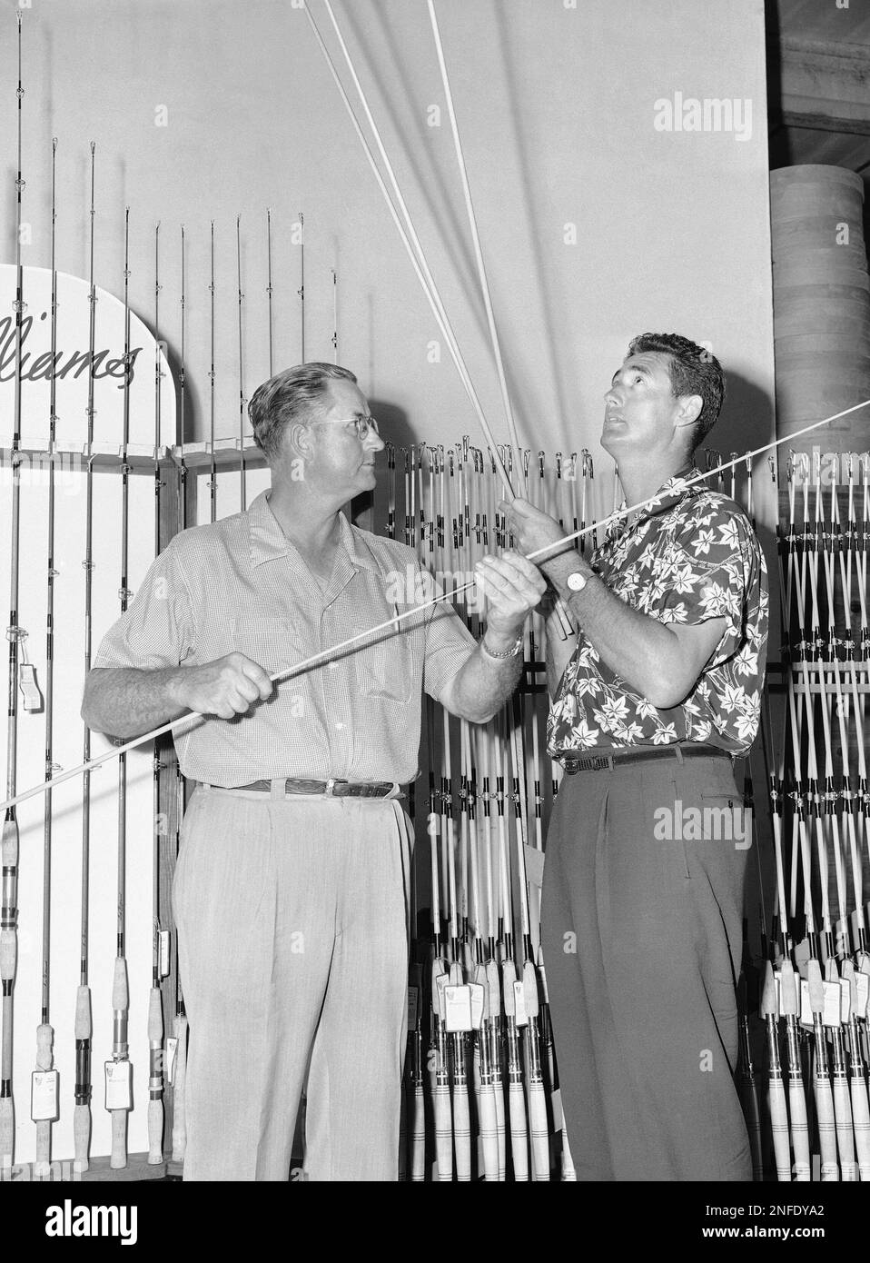 Ted Williams, right, who says this is his last season in baseball, tries  out a handful of unfinished rods at a fishing tackle plant in Miami, with  Lee Cuddy, left, who is