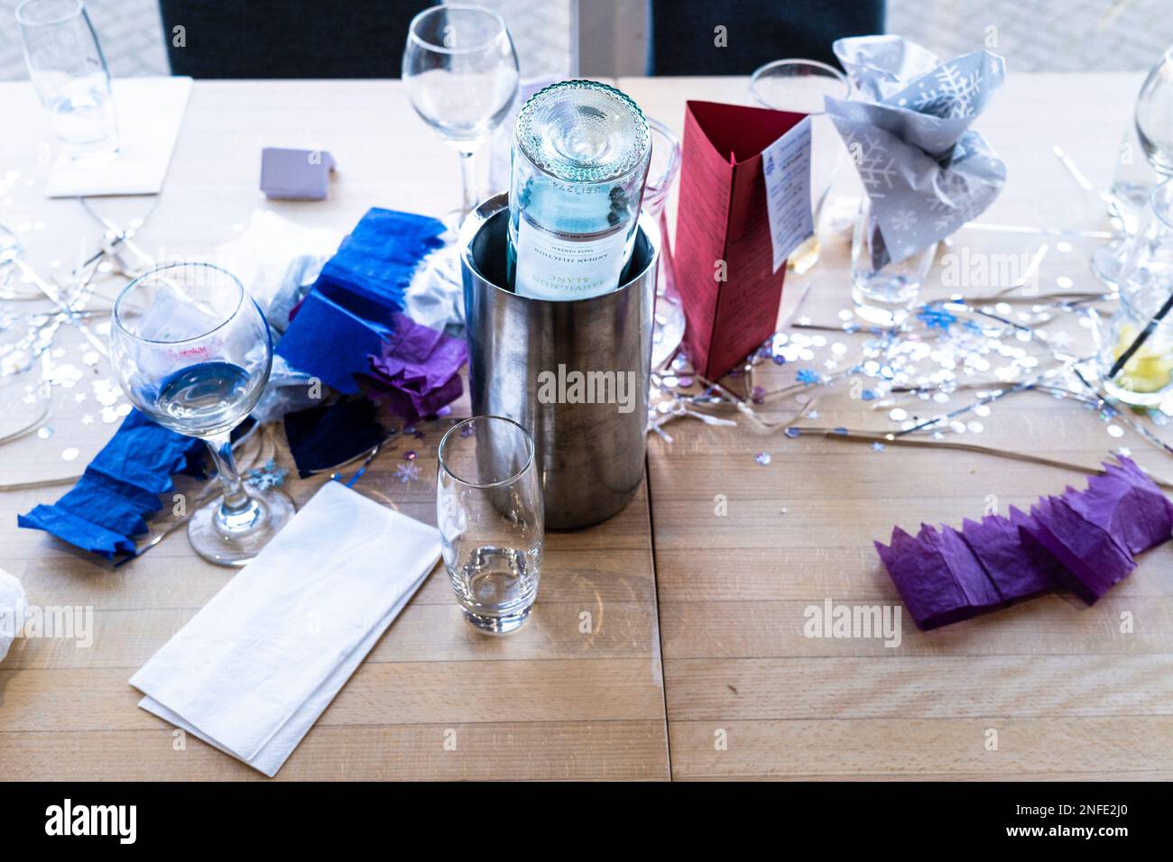 An empty finished wine bottle upside down in an ice bucket on a table in a restaurant. Stock Photo