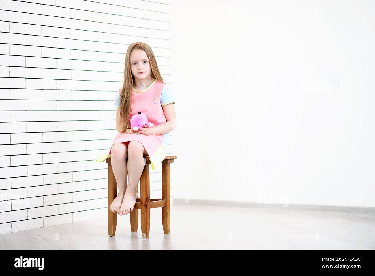 little girl is sitting on a chair and posing on the camera Stock Photo ...