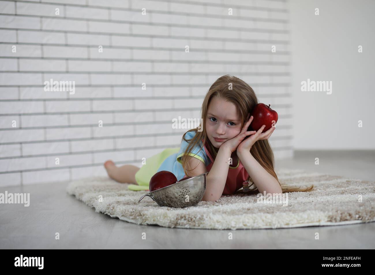 little girl lies on the floor and eats an apple Stock Photo - Alamy