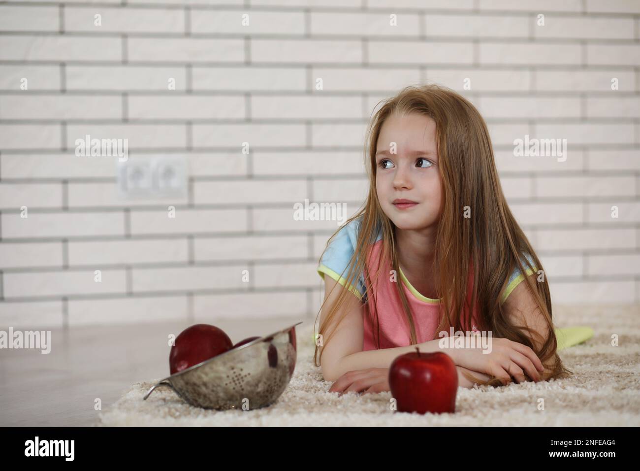 little girl lies on the floor and eats an apple Stock Photo - Alamy