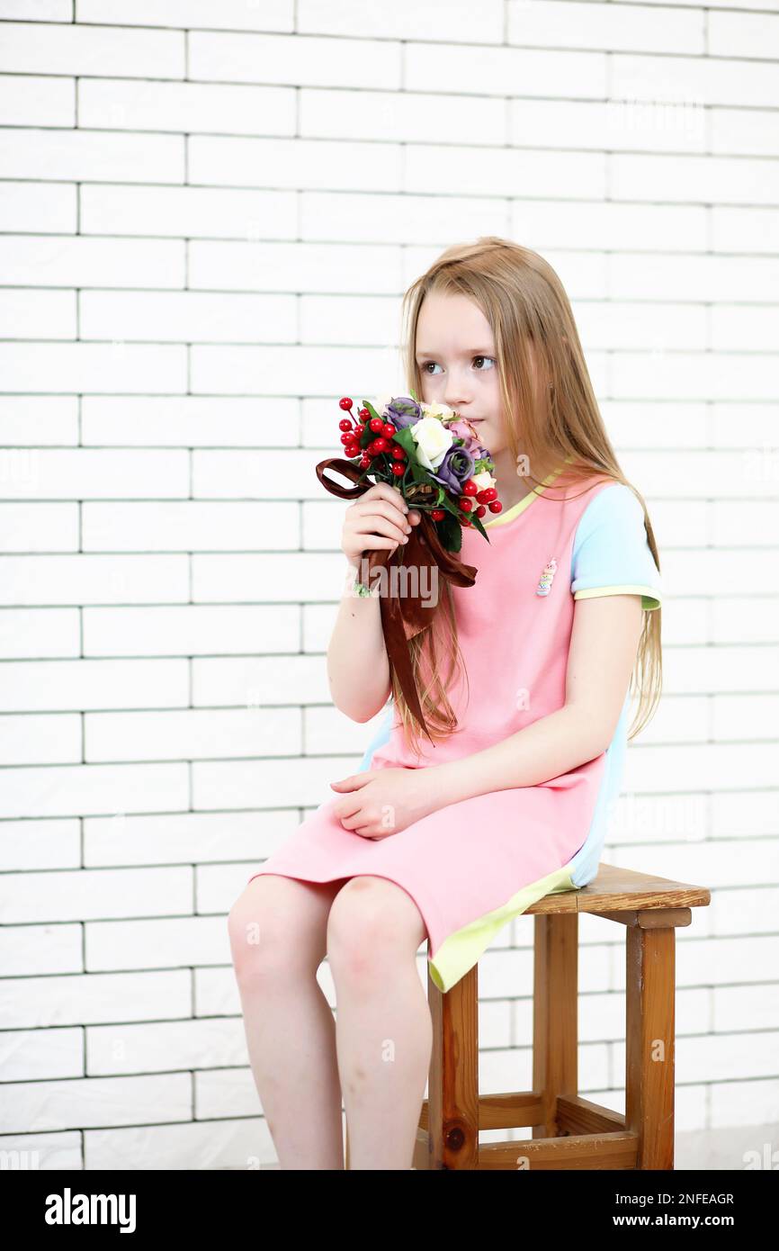 little girl is sitting on a chair and posing on the camera Stock Photo ...