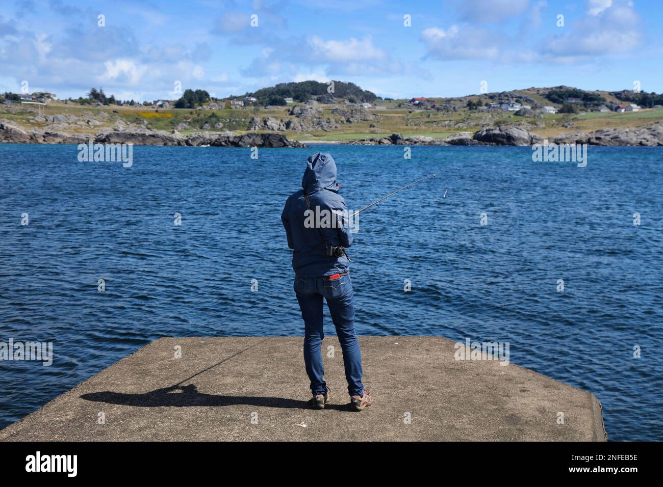 Norway spin fishing. Woman angler at a pier in Karmoy island, Rogaland region. Stock Photo