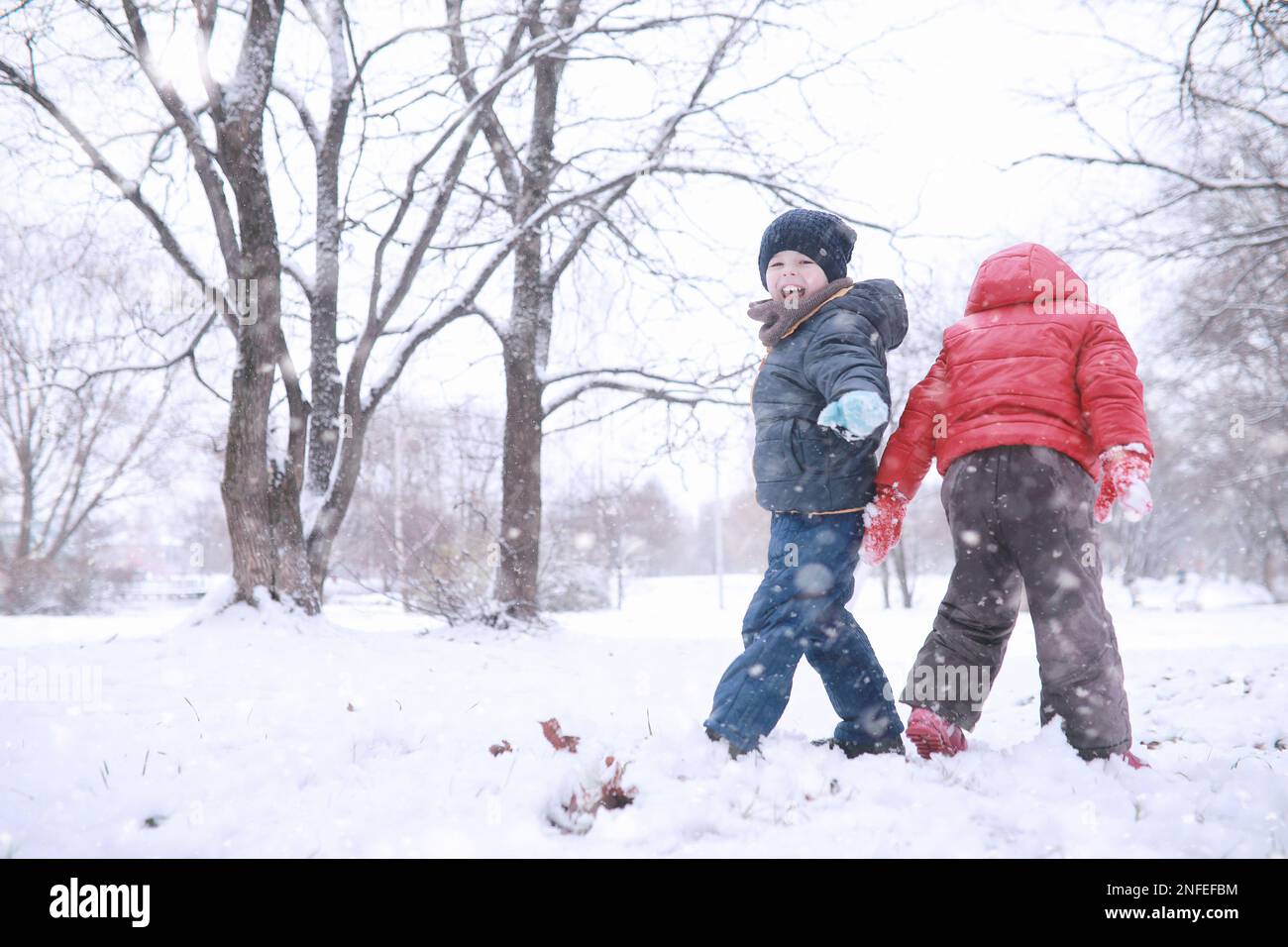 Kids walk in the park with first snow Stock Photo - Alamy