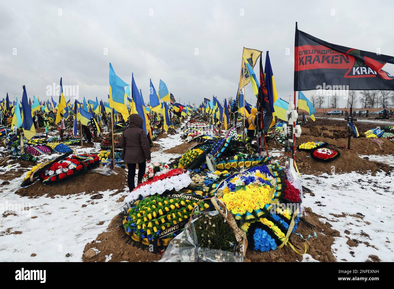 KHARKIV, UKRAINE - FEBRUARY 16, 2023 - National flags fly above the graves of perished Ukrainian defenders on the Alley of Glory at cemetery N18, Khar Stock Photo