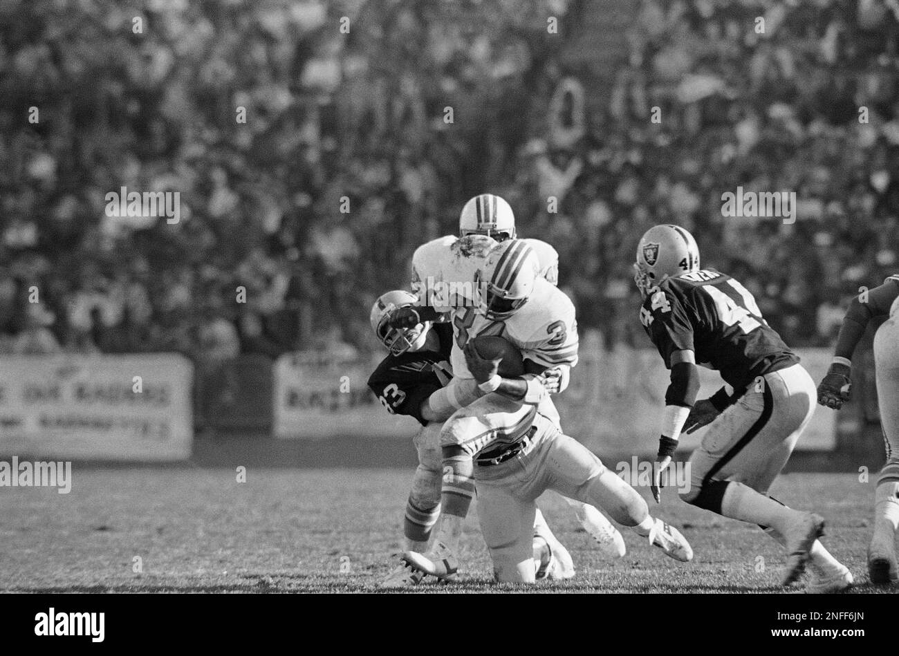 Houston Oilers Earl Campbell (34) is hauled down by Raiders Ted Hendricks  (83) after seven years