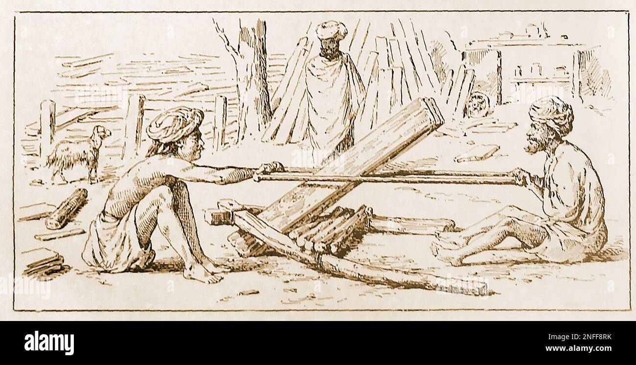 A late 19th century illustration showing village carpenters India, cutting planks of wood. Stock Photo