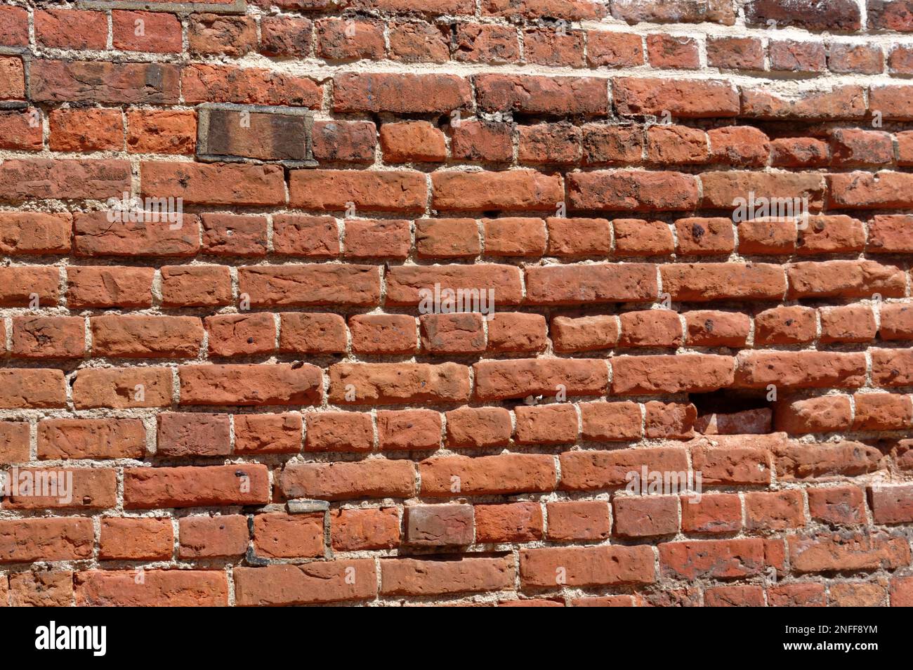 Old, English bond laid brick wall in poor, eroded condition. Stock Photo