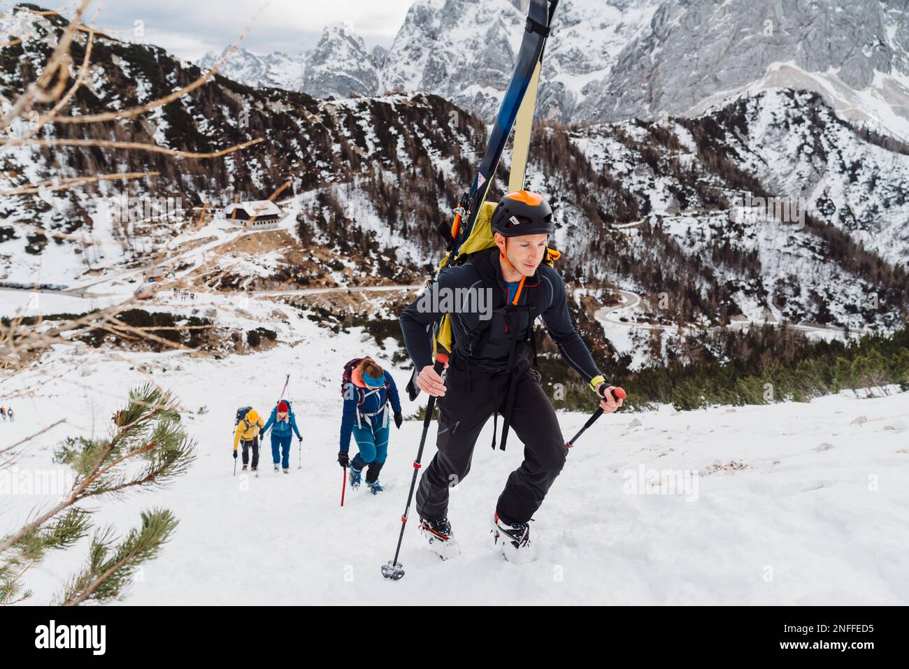 Group of mountaineers climbing up a snowy mountain with skies on their backs  Stock Photo