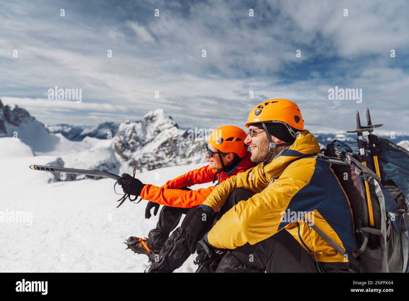 Side view of two smiling hikers in winter hiking gear sitting in the