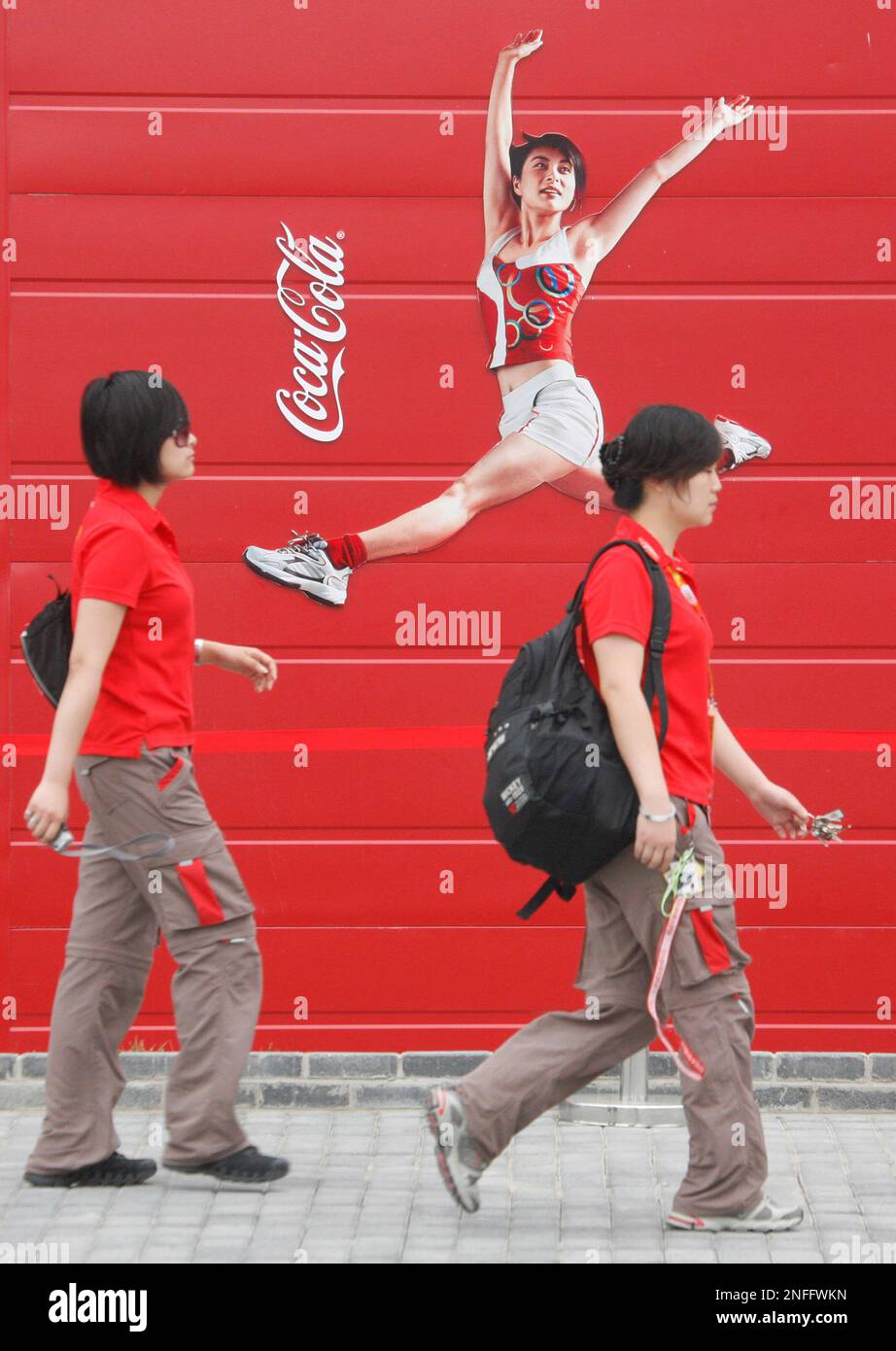 Two women walk past a Coca-Cola sign on the Olympic Green at the 2008 Beijing Olympics in Beijing on Saturday, Aug. 9, 2008. Coca-Cola, the world's biggest beverage company, moved to expand its operations in the fast-growing Chinese market Wednesday with a $2.5 billion bid for major juice maker China Huiyuan Juice Group Ltd. (AP Photo/Peter Morgan) Stock Photo