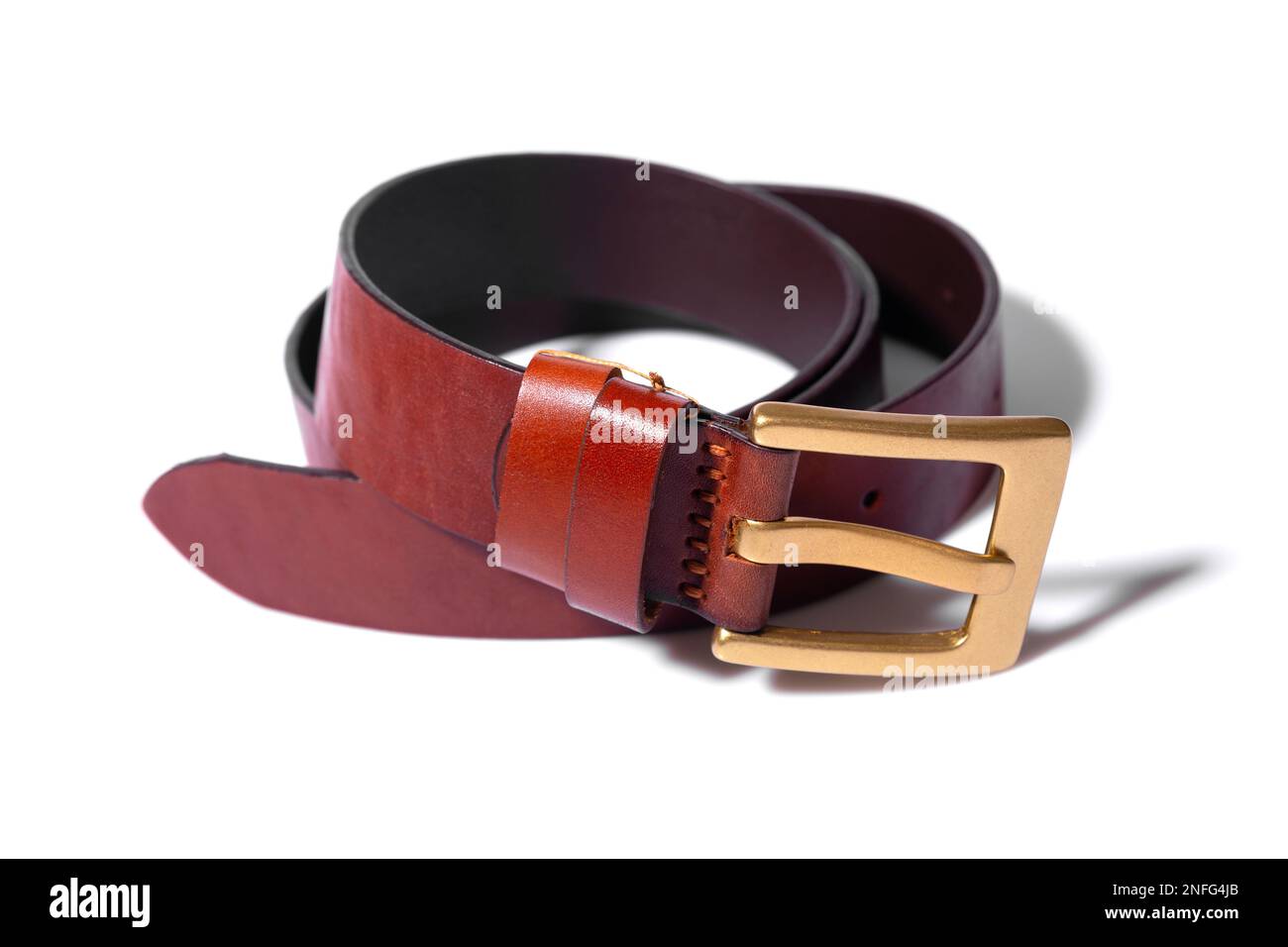 A rolled-up brown leather belt with a metal buckle on a white background is isolated. Place for advertisement, logo, label, mockup, mock-up. Stock Photo