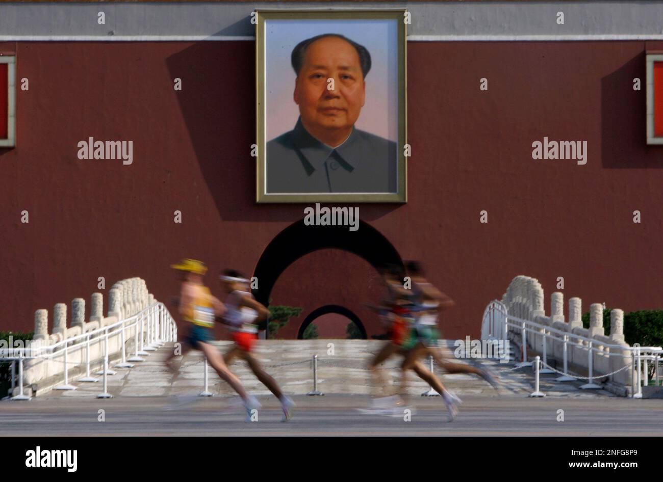 Runners cross by Tiananmen gate and a portrait of the late Chinese ...