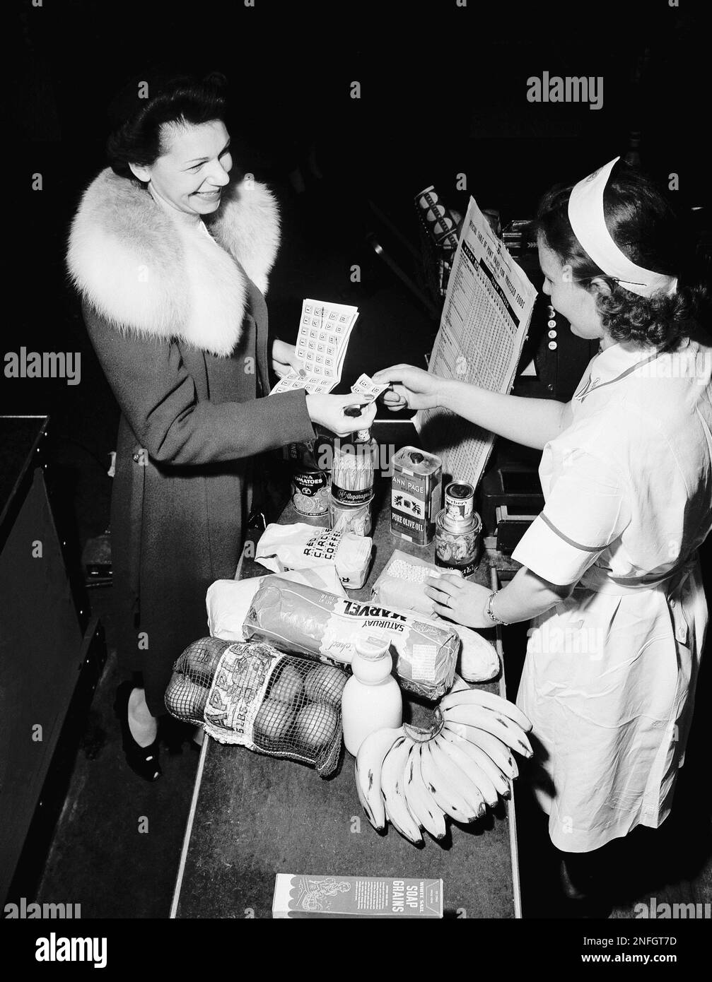 A shopper pays for her groceries using cash and ration coupons in