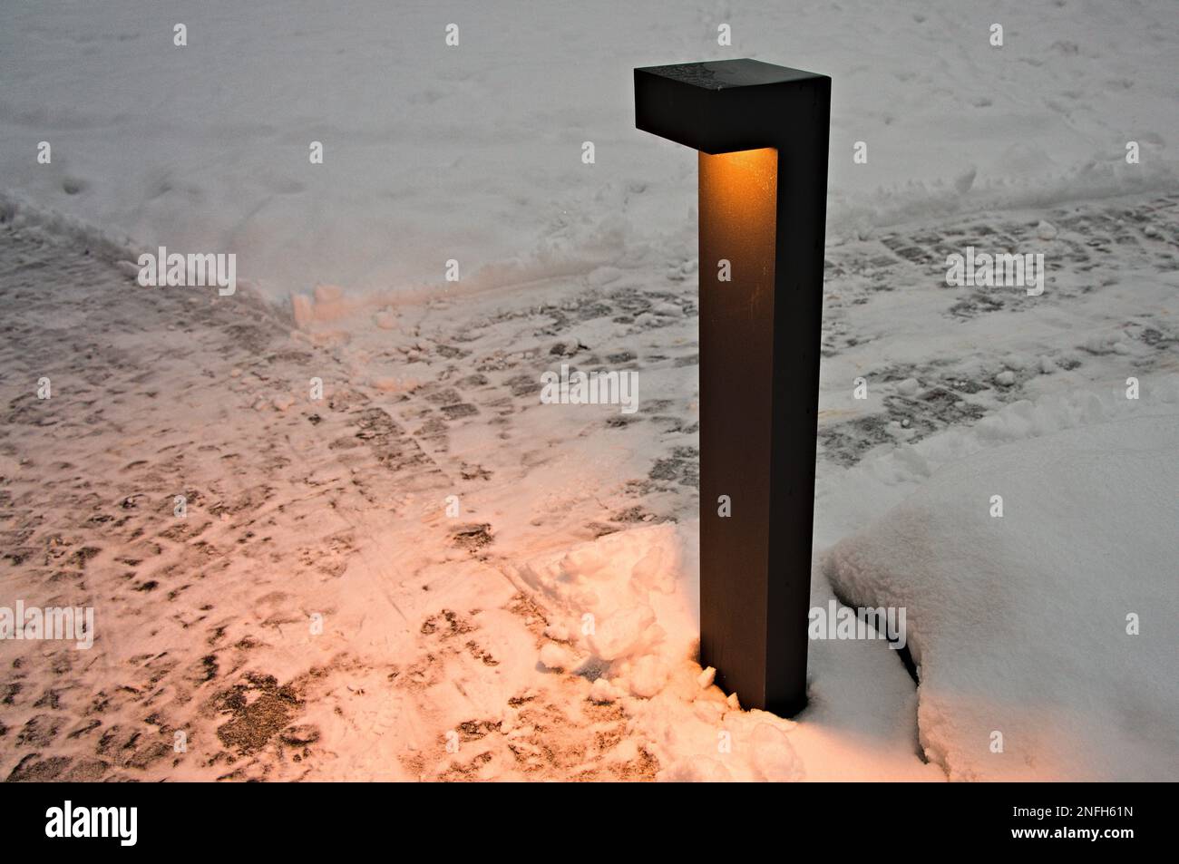 Metalic lamp illuminates snowy cobbles Stock Photo