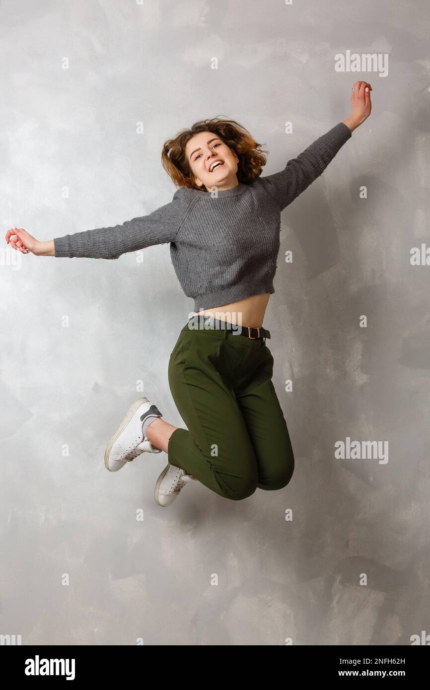 Full length portrait of a cheerful casual asian woman jumping isolated ...