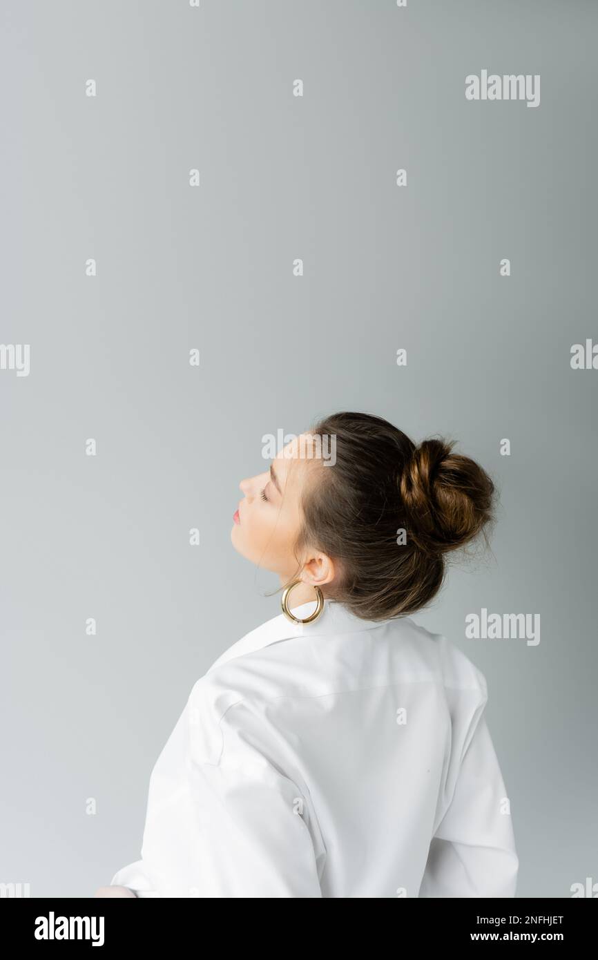 young model in white shirt and hoop earring posing isolated on grey with copy space,stock image Stock Photo