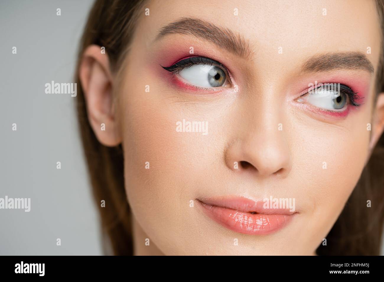Close up view of young fair haired woman with pink eye shadow isolated on grey,stock image Stock Photo