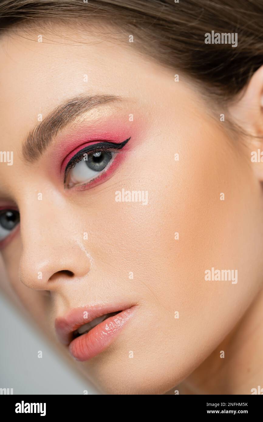 Cropped view of woman with pink eye shadow and eye liner looking at camera isolated on grey,stock image Stock Photo