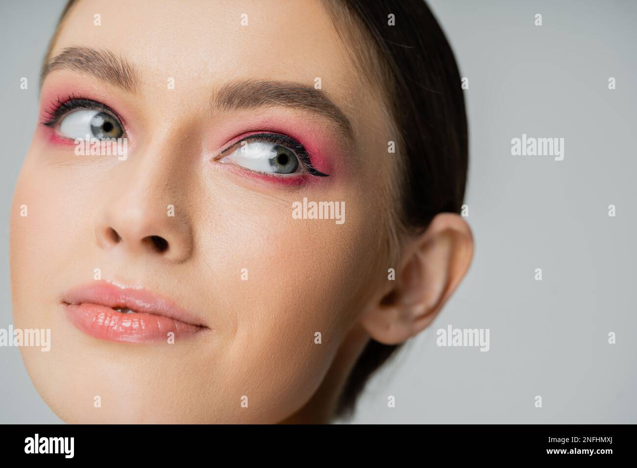 Close up view of woman with pink eye shadow and eye liner isolated on grey,stock image Stock Photo