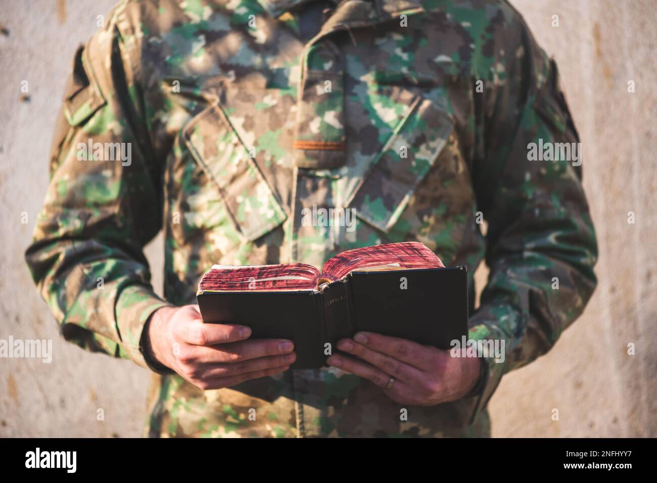 Soldier dressed in camouflage uniform holding a bible in his hand
