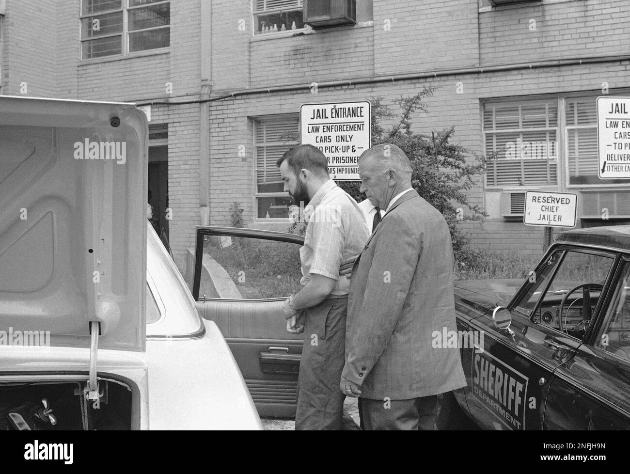 Gary Steven Krist, bearded and handcuffed, is placed in a car outside